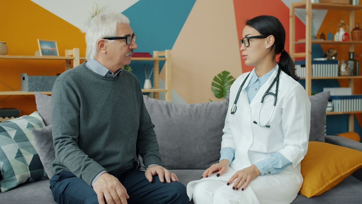 A doctor talking with an older patient on a couch